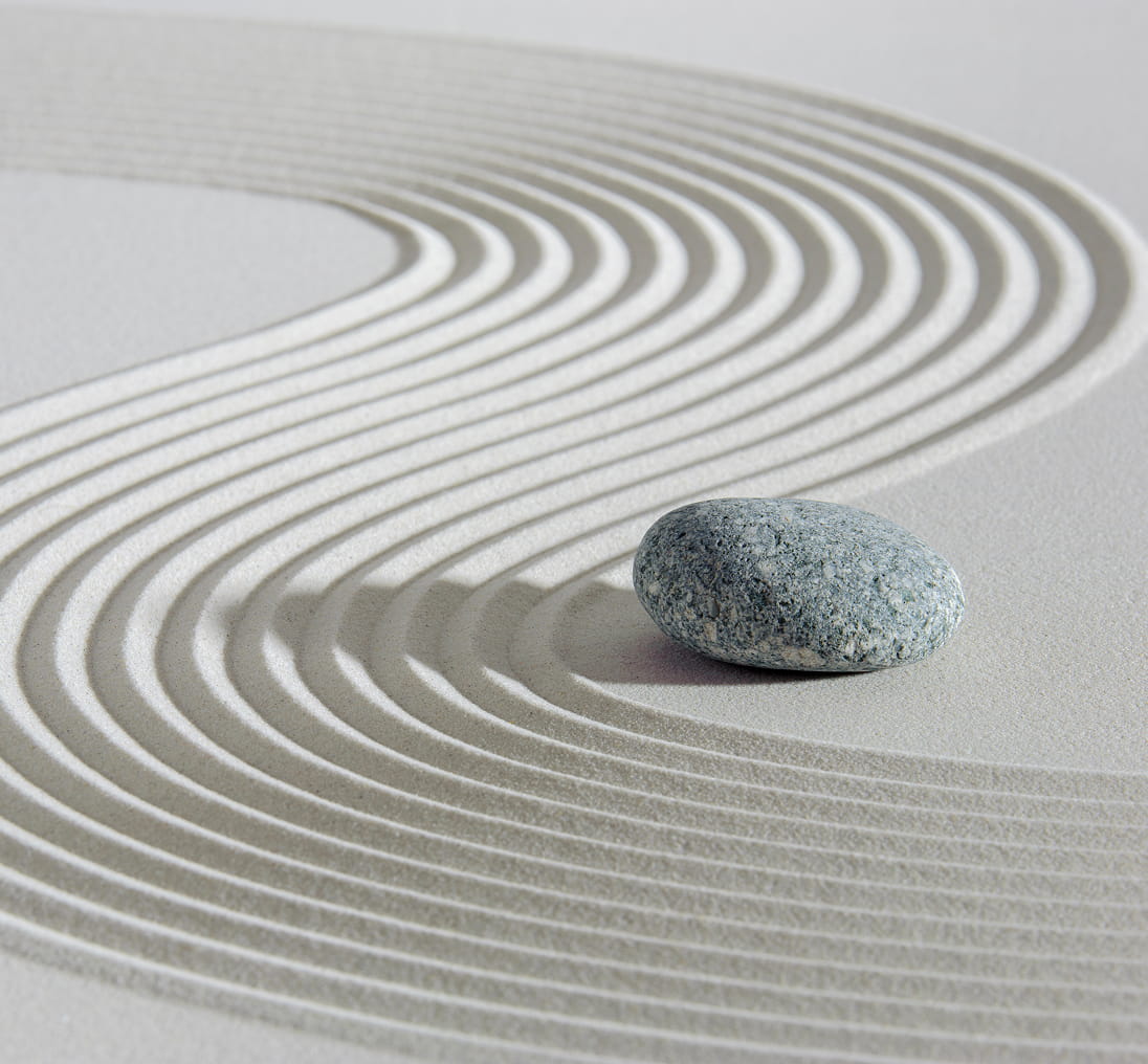 a zen garden with waves in the sand with a rock sitting near it